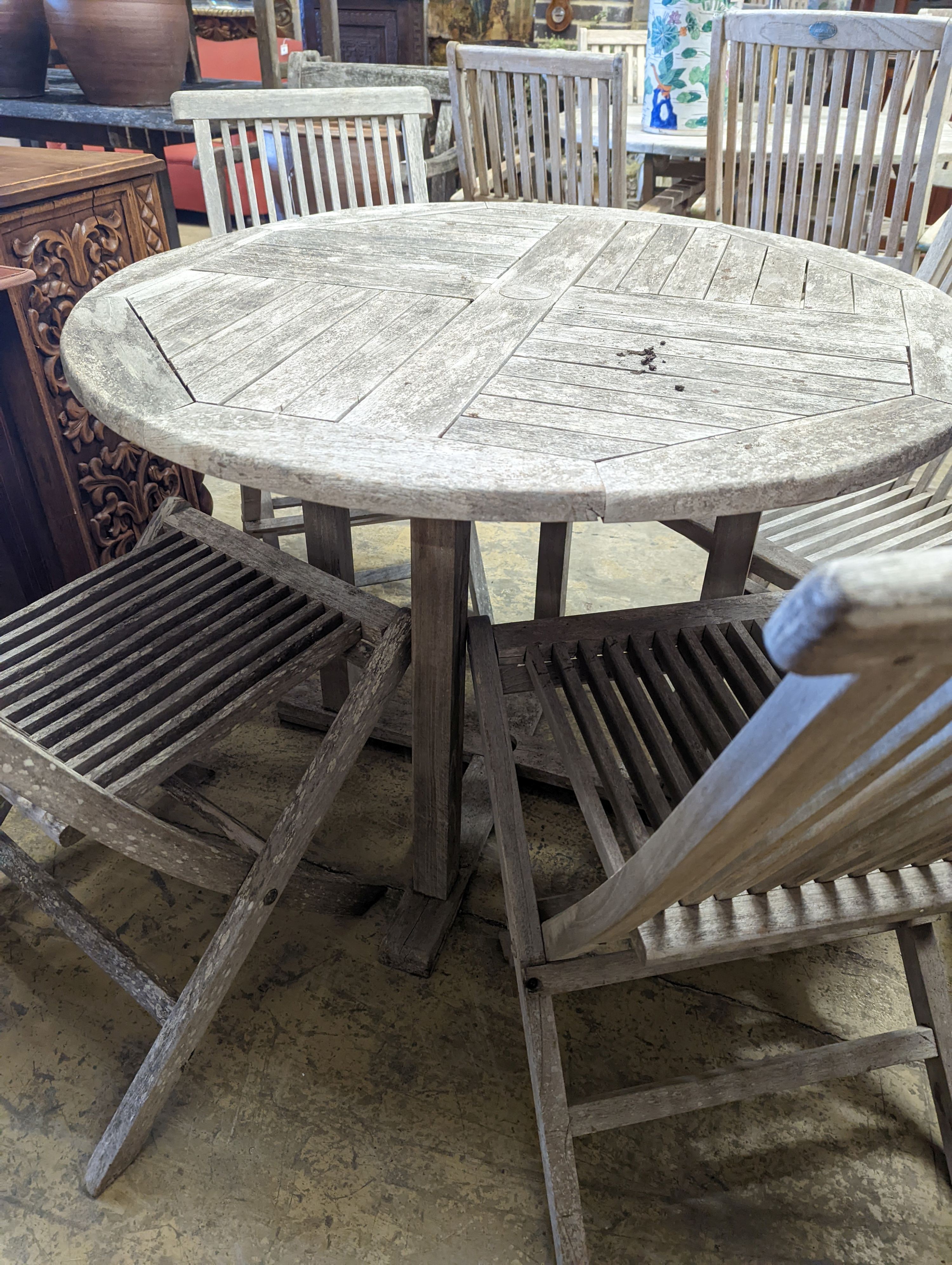 A circular weathered teak garden table, diameter 100cm, height 75cm together with four folding chairs